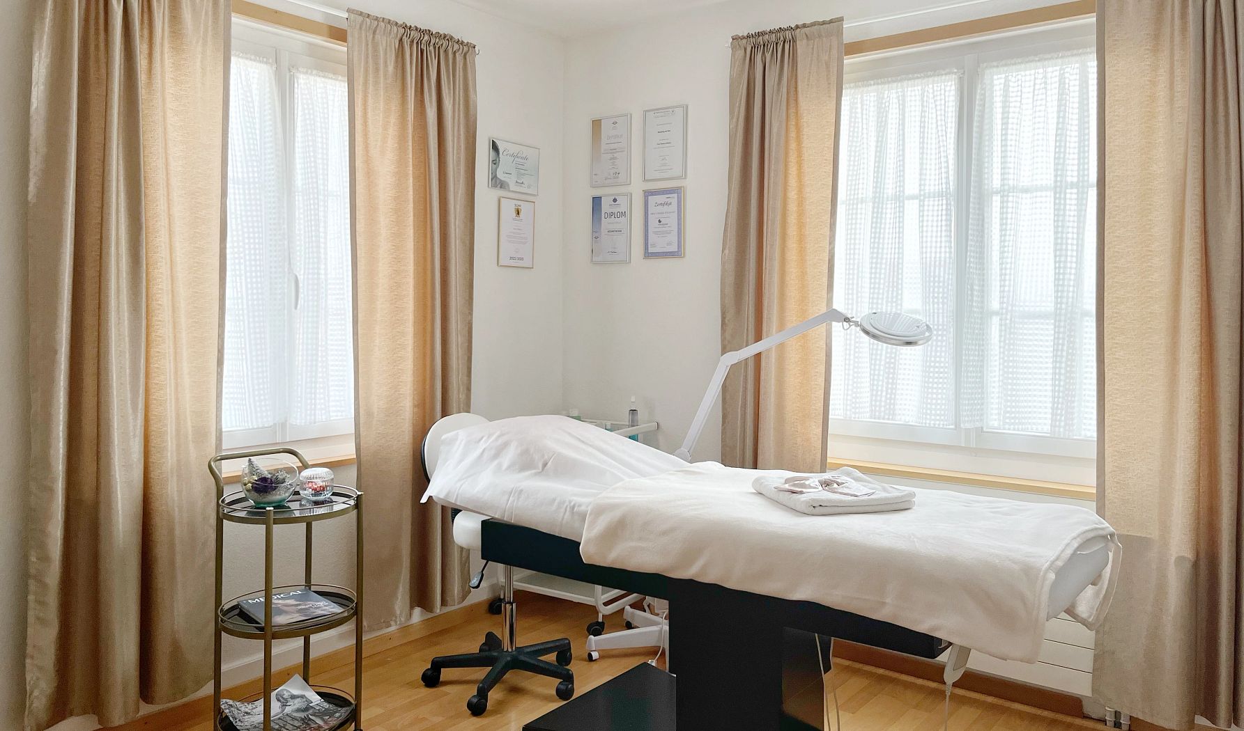 La cabine de Still&Art Beauty : table de soin, lampe loupe, rideaux champagne et diplômes au mur